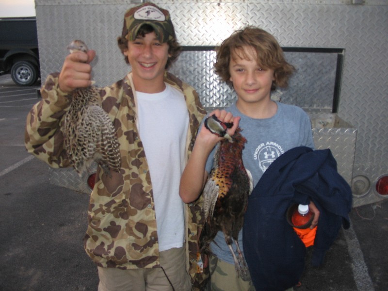 The boys are holding dead birds. In the morning they shot 45 and in the afternoon 44 birds